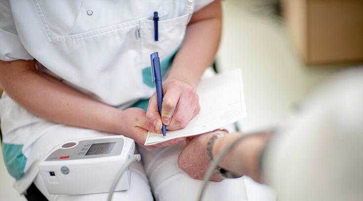 Pflegekraft mitt Blutdruck einer Patientin