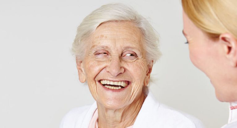 Seniorin lacht weiblicher Pflegekraft an