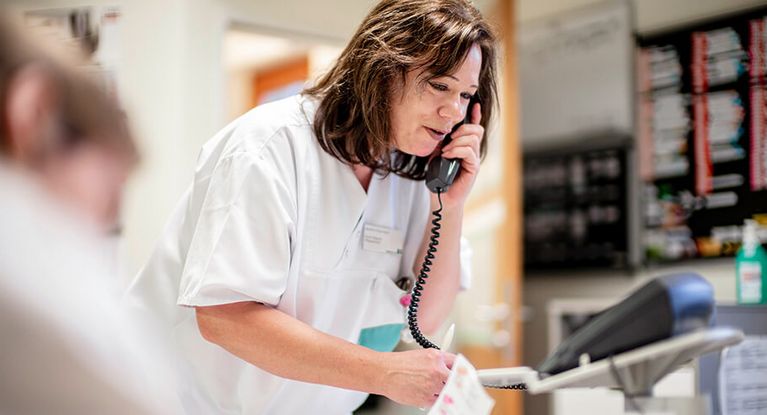 Pflegekraft telefoniert im Stationszimmer