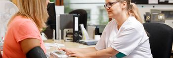 Pflegekraft misst Blutdurck einer Patientin