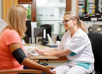 Pflegekraft misst Blutdurck einer Patientin