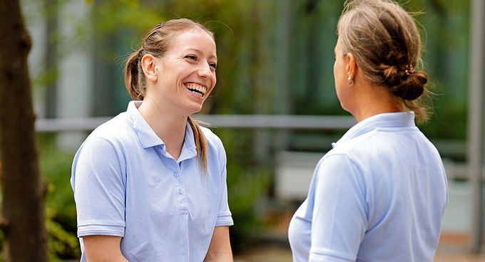 Zwei Pflegekräfte sprechen miteinander