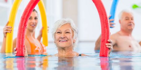 Patientinnen üben mit Poolnudeln im Wasser