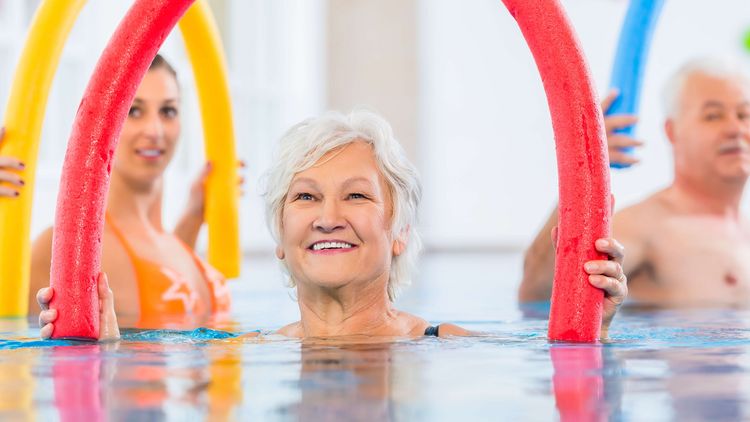 Patientinnen üben mit Poolnudeln im Wasser
