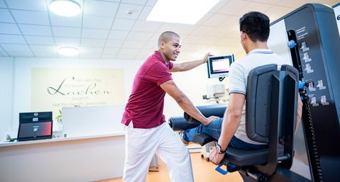 Therapeut unterstützt Patient in der Medizinische Trainingtherapie
