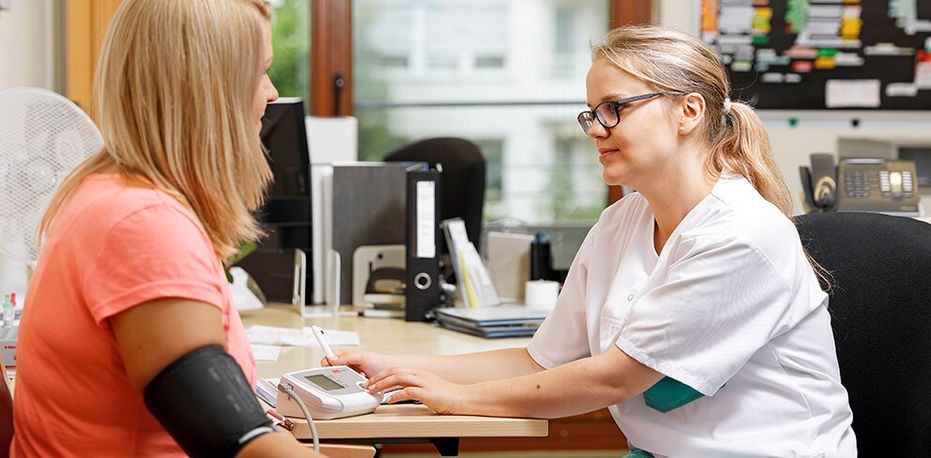 Pflegekraft misst Blutdruck einer Patientin