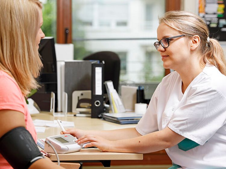 Pflegekraft misst Blutdruck einer Patientin