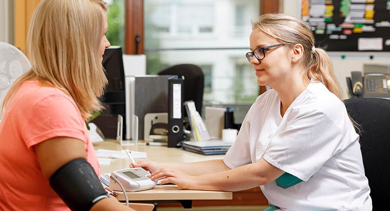 Aufnahmeuntersuchung Pflegekraft misst Blutdruck einer Patientin