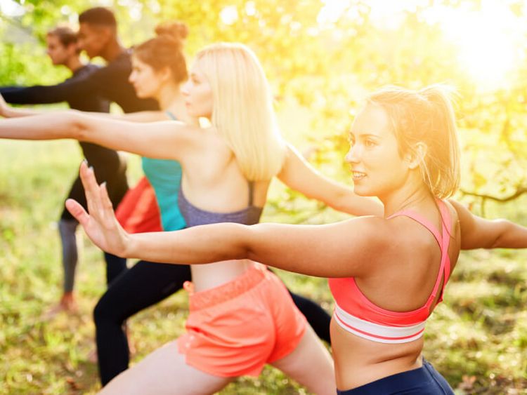 eine Gruppe junger Menschen macht Thai Chi draußen im Park