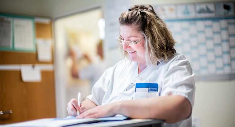 Pflegekraft schreibt in Patientenakte Pflegekraft schreibt in Patientenakte