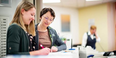 Patientinnen tragen sich an der Rezeption in eine Liste ein