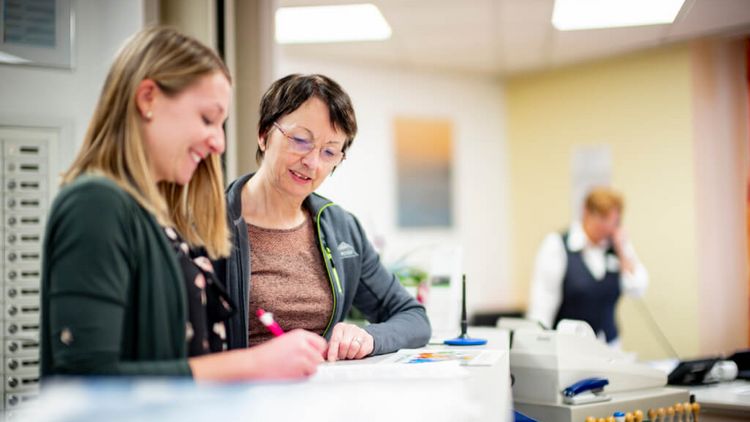Patientinnen tragen sich an der Rezeption in eine Liste ein