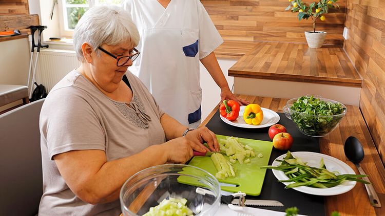 Patientin schneidet Gemüse in der Lehrküche