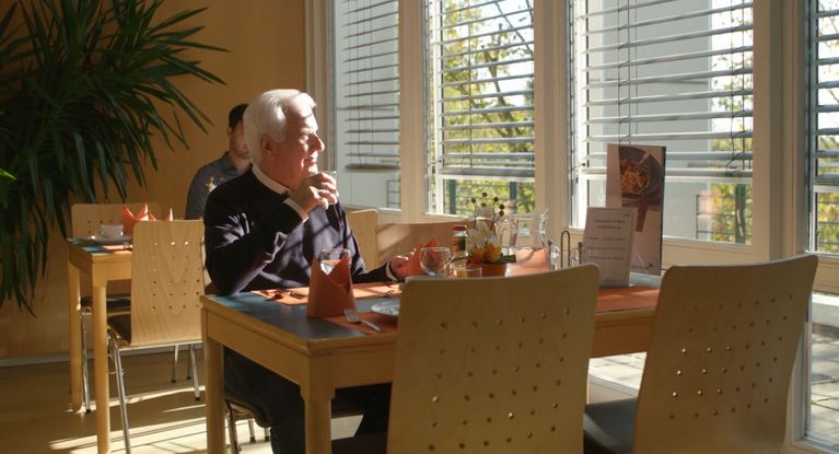 Ältere Patient sitzt im Speisesaal