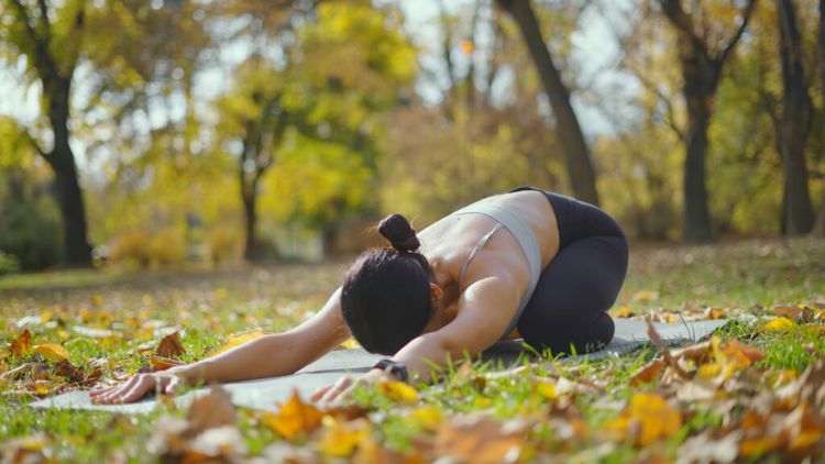 Junge Frau macht Yoga auf einer Yogamatte im Park