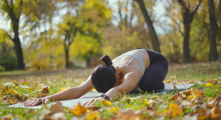 Junge Frau macht Yoga auf einer Yogamatte im Park